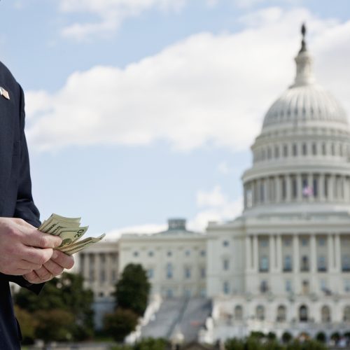 A politician stands outside of the U.S. capitol while counting money