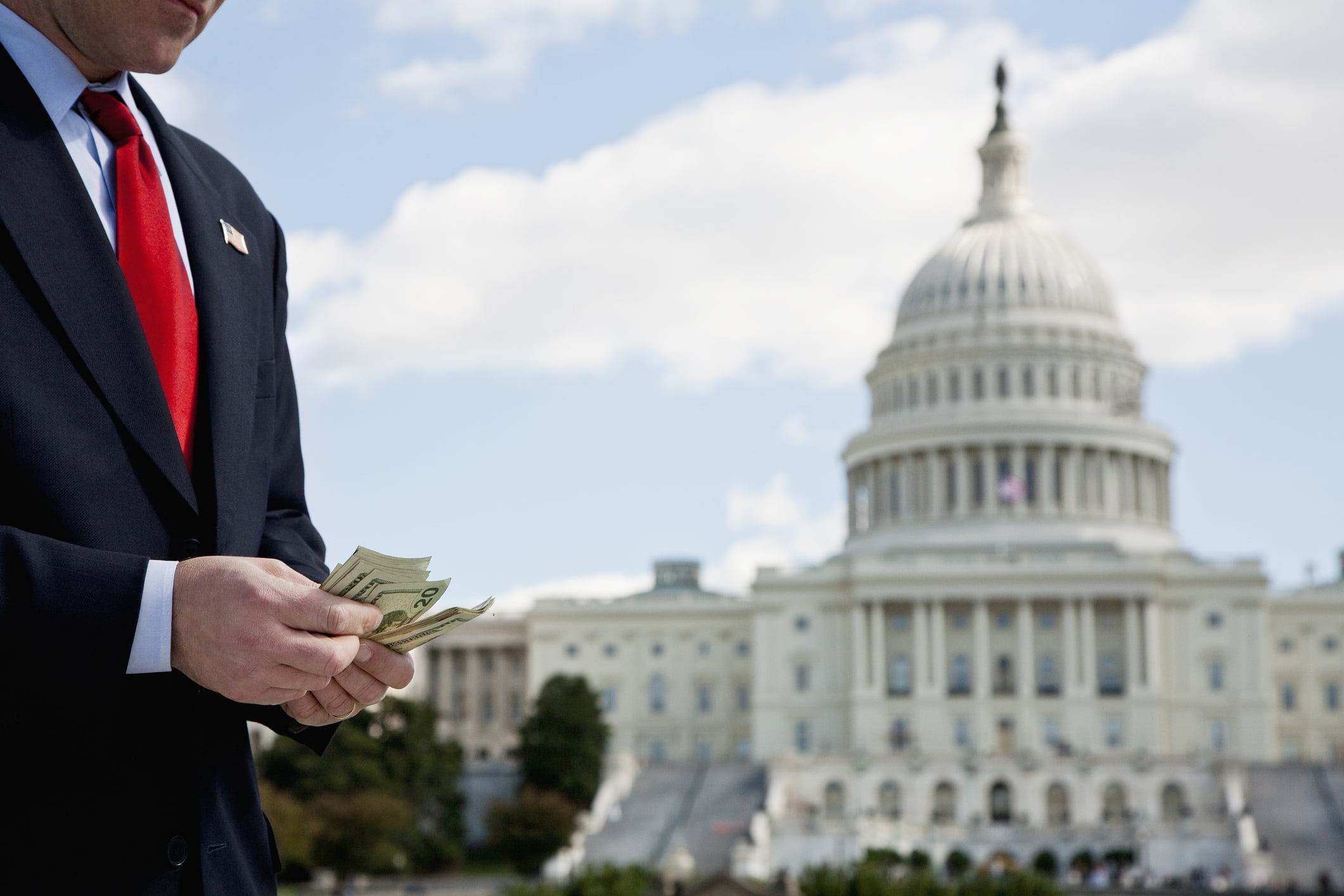 A politician stands outside of the U.S. capitol while counting money