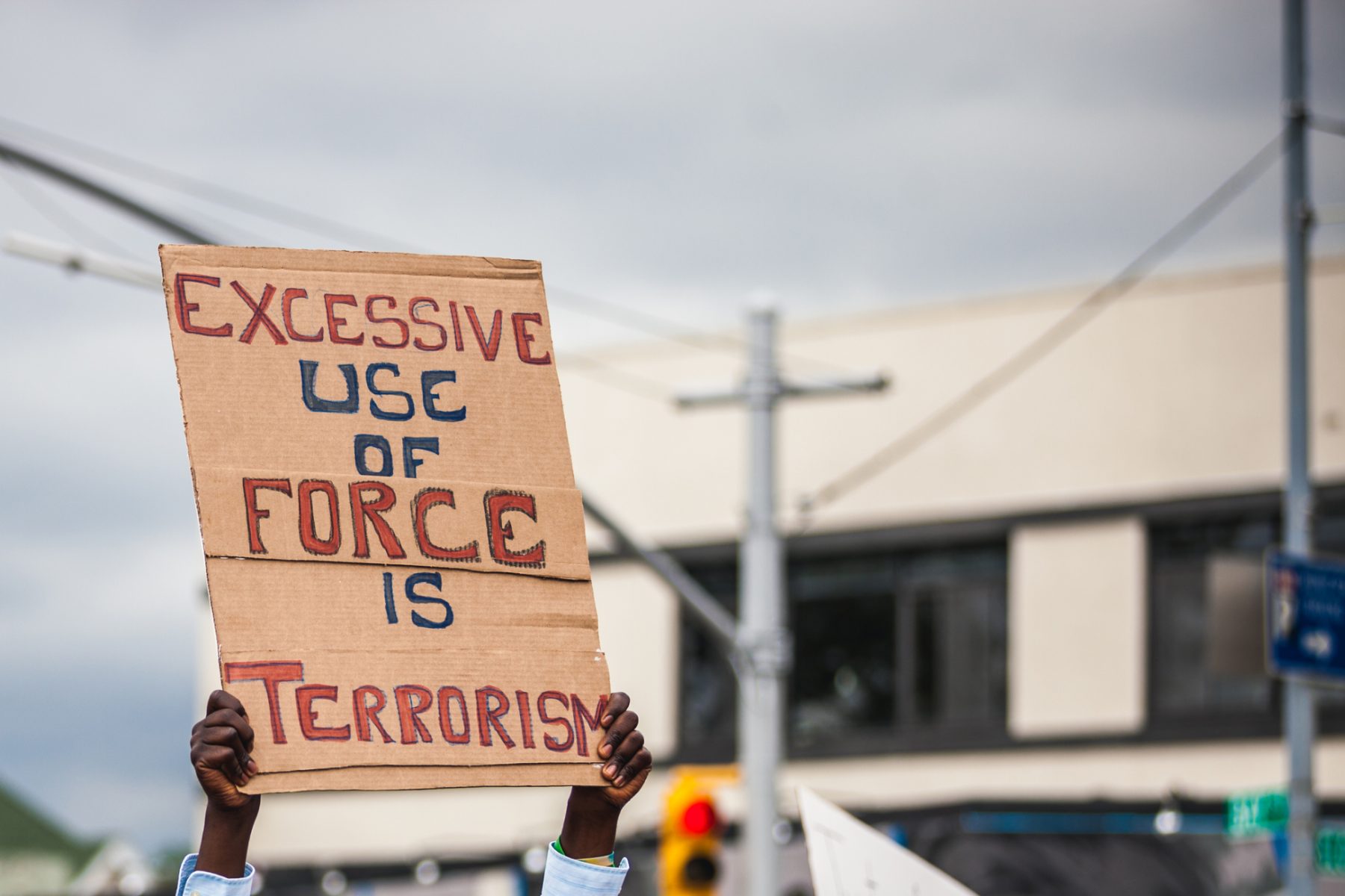 A sign is held up during a civil rights protest that states, “Excessive Use of Force Is Terrorism.”