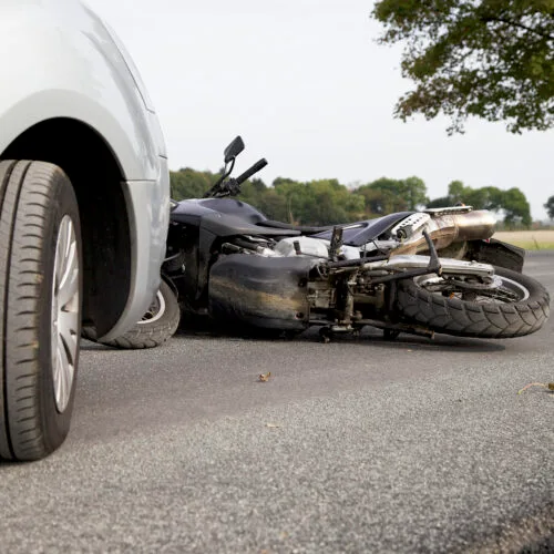 Close-up of a motorcycle lying on the road after a collision with a car.